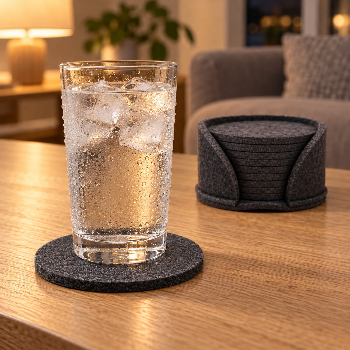 Iskaldt glass med dugg på mørk grå filtbrikke, holder med brikker bak