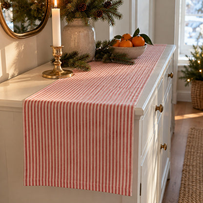 Striped Christmas table runner on a white hallway chest of drawers with a candlestick and clementines