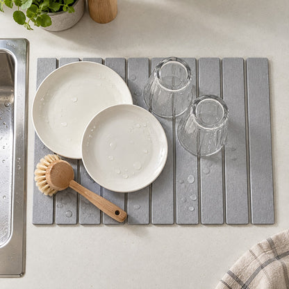 Stone mat in use beside the kitchen sink with plates, glasses and a washing-up brush