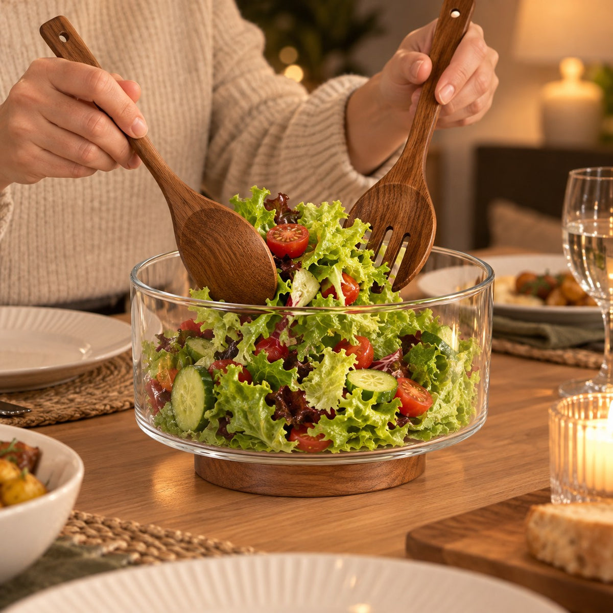 Salatbolle i glass på trefot med salatbestikk på et middagsbord