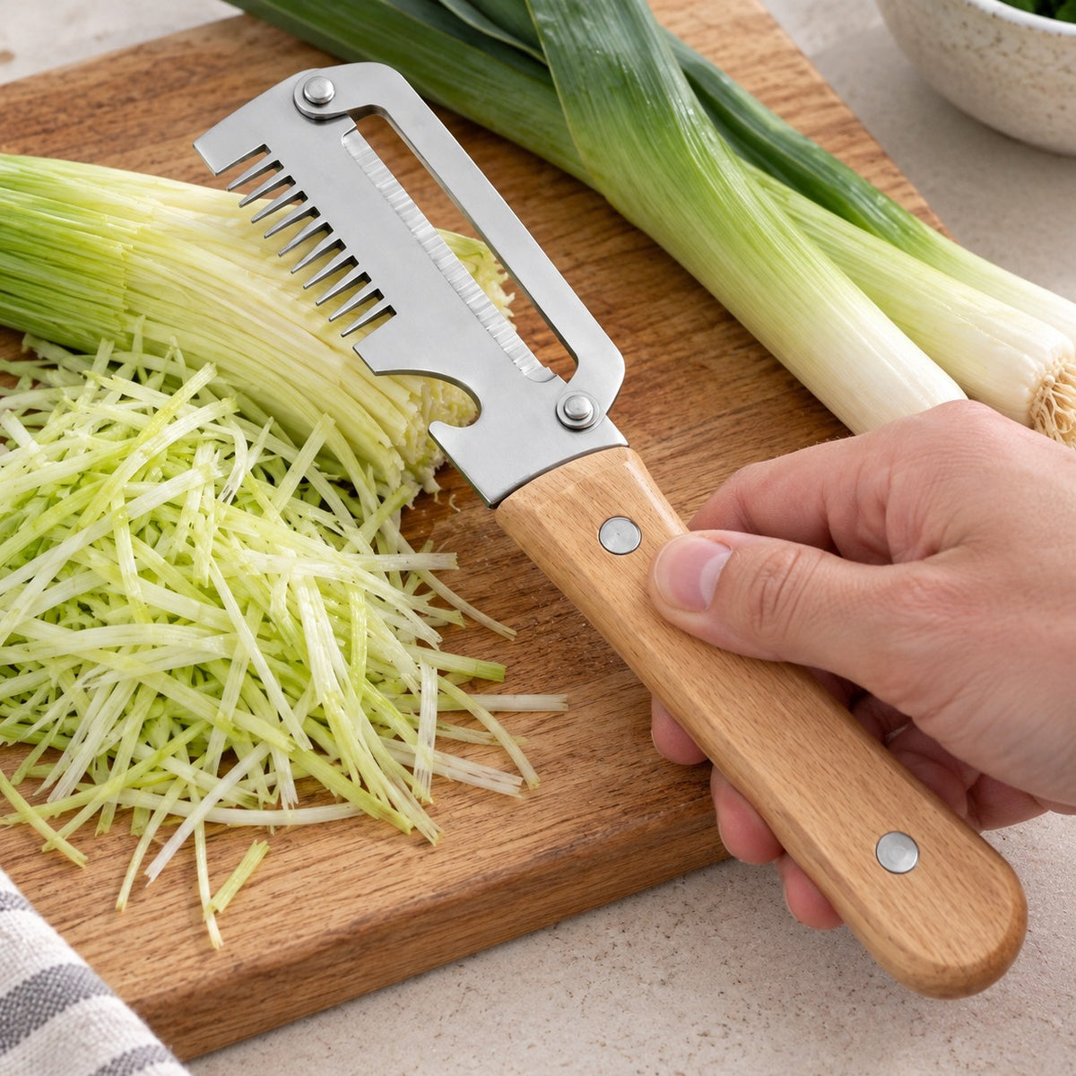 A hand shredding leek with a wooden-handled vegetable cutter on a chopping board